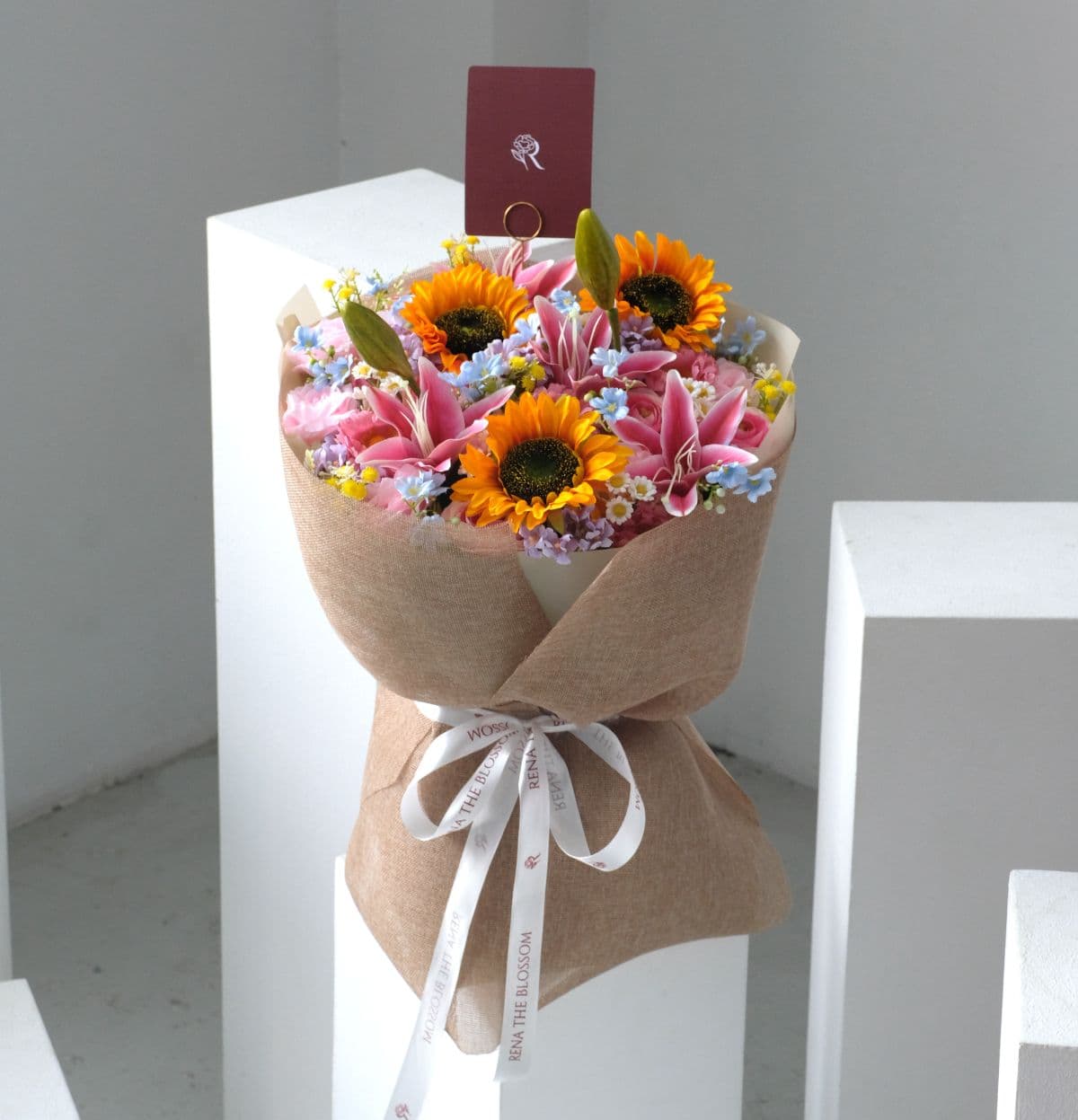 Sunrise In Brown (Artificial) - Yellow sunflower, pink ranunculus & forget-me-not in an artificial warm sunrise palette. - Rena The Blossom Jakarta